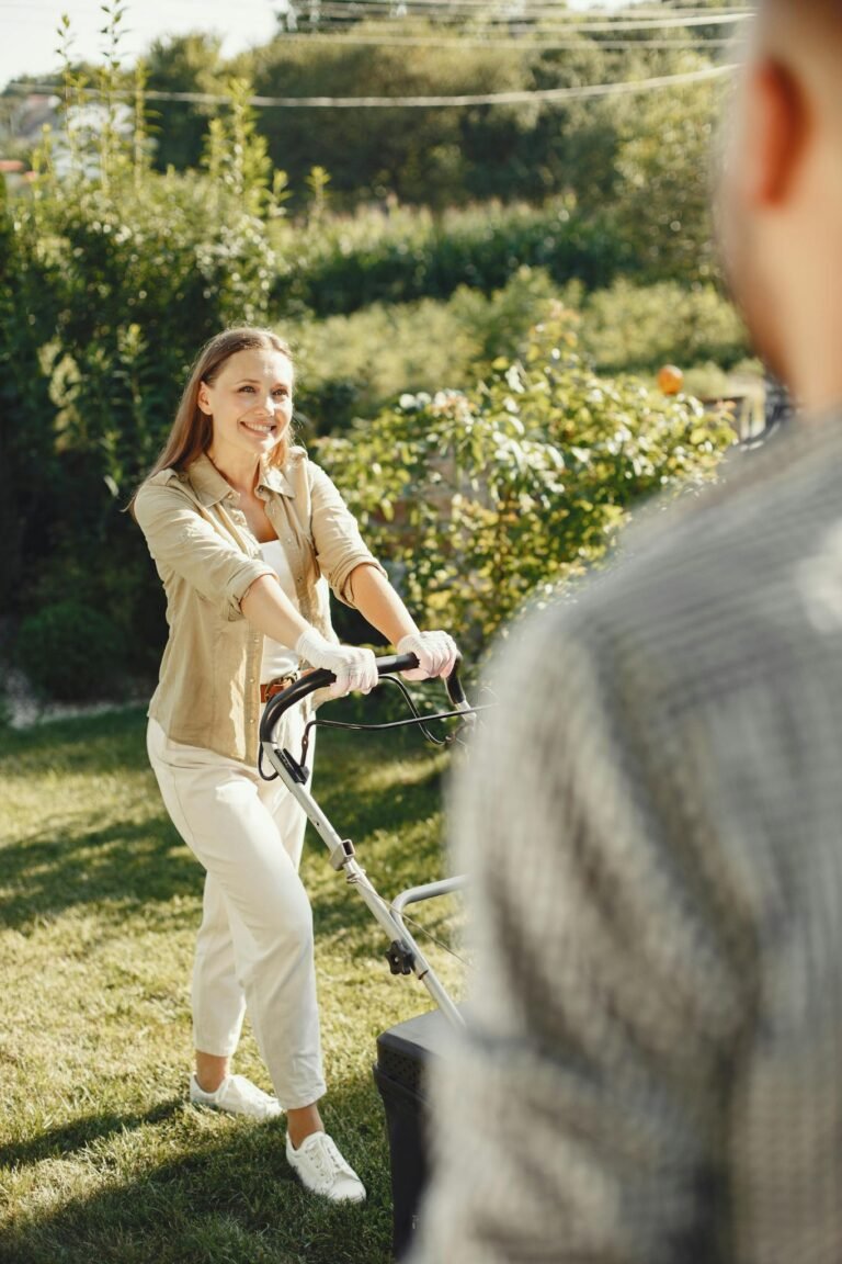 Smiling woman mowing the lawn in a sunny backyard garden.